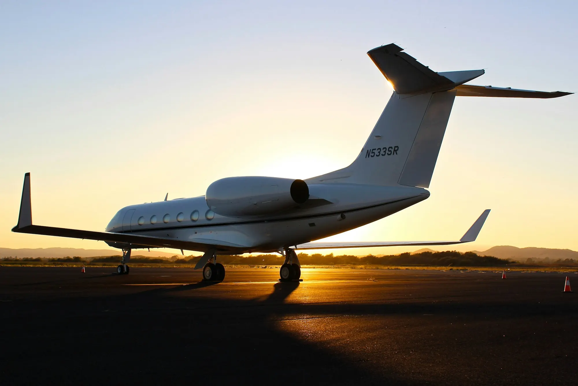 A large-cabin business jet on the ramp at sunset
