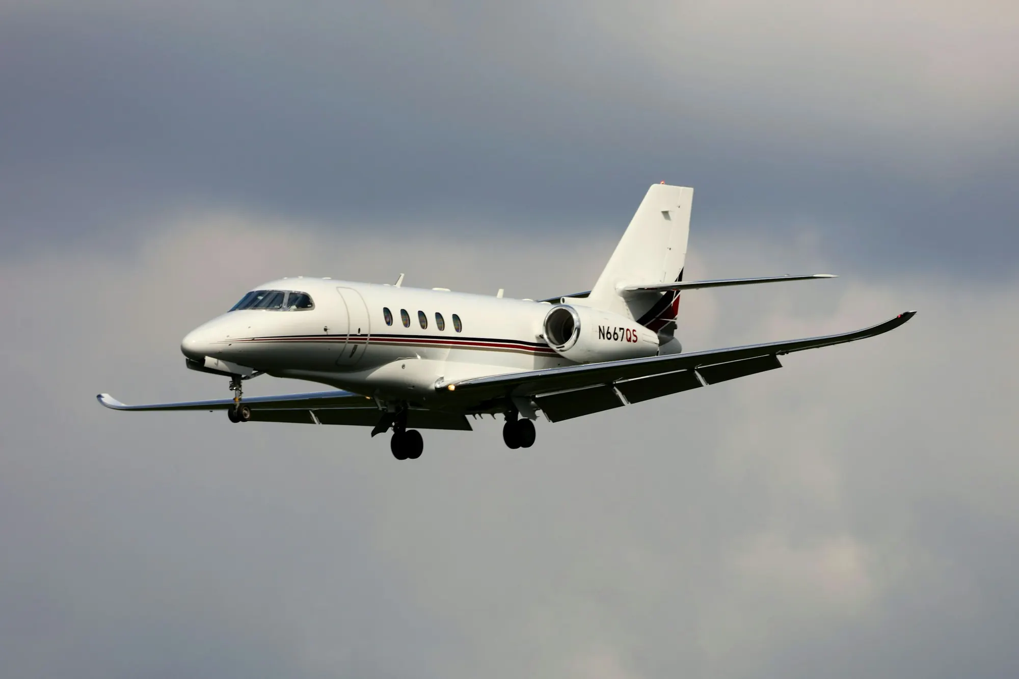 A white business jet in flight above the clouds
